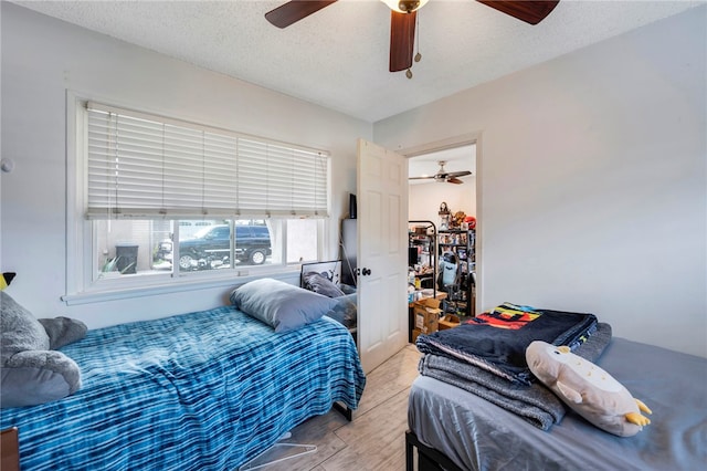 bedroom featuring light wood-type flooring, ceiling fan, and a textured ceiling