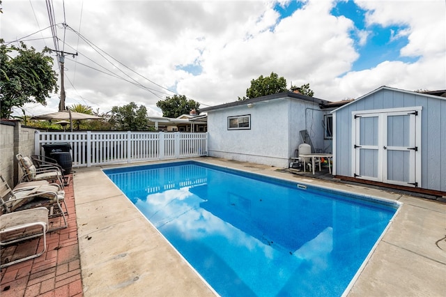 view of swimming pool with a storage shed and a patio area