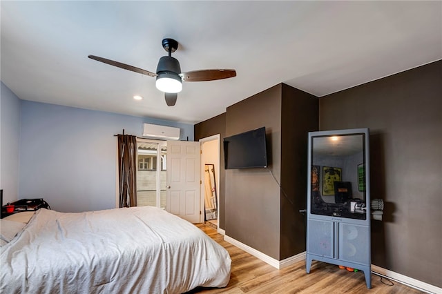 bedroom featuring light hardwood / wood-style floors, ceiling fan, and a wall unit AC