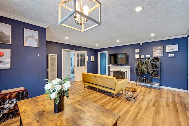 dining area with a notable chandelier, light hardwood / wood-style floors, crown molding, and a textured ceiling