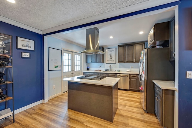 kitchen with stainless steel appliances, island exhaust hood, light hardwood / wood-style floors, a center island, and sink