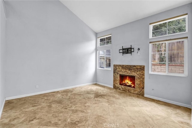 unfurnished living room with a high end fireplace, high vaulted ceiling, and light tile patterned flooring