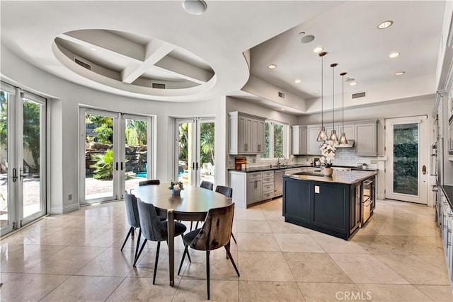 kitchen with french doors, tasteful backsplash, a center island, gray cabinets, and pendant lighting