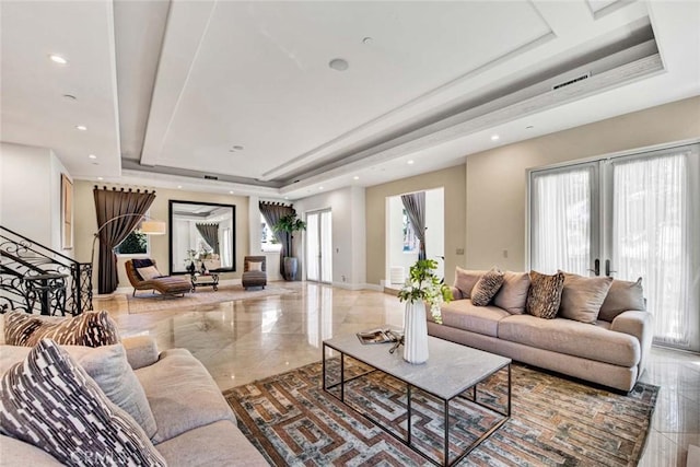living room with french doors, plenty of natural light, and a raised ceiling