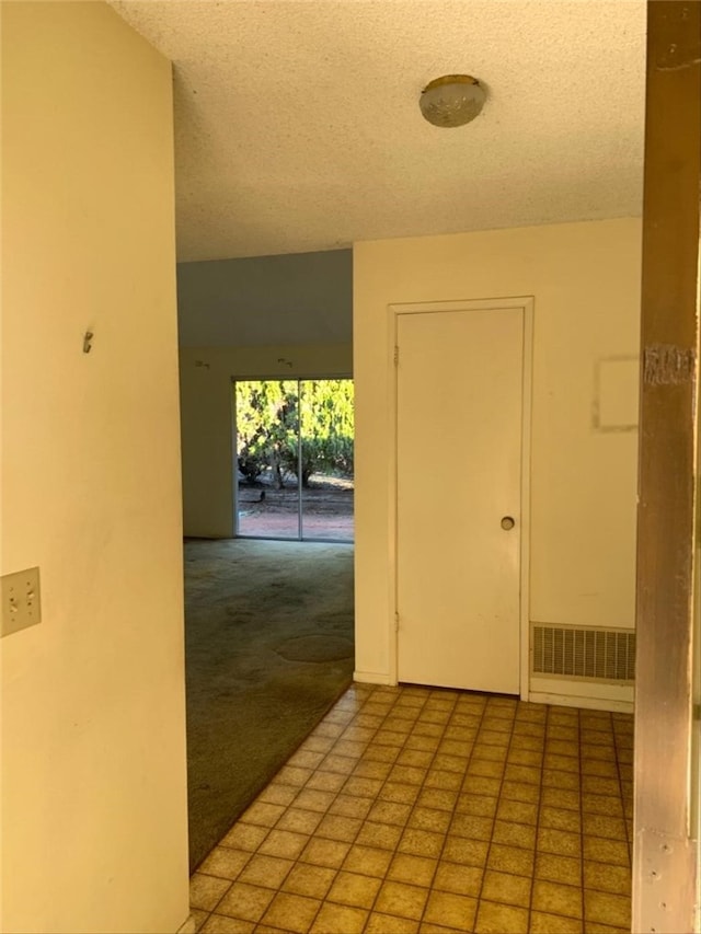 hall featuring light carpet and a textured ceiling