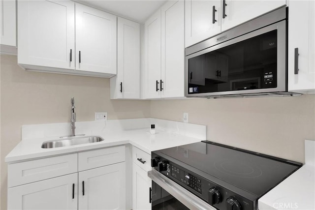 kitchen featuring sink, electric range oven, and white cabinets