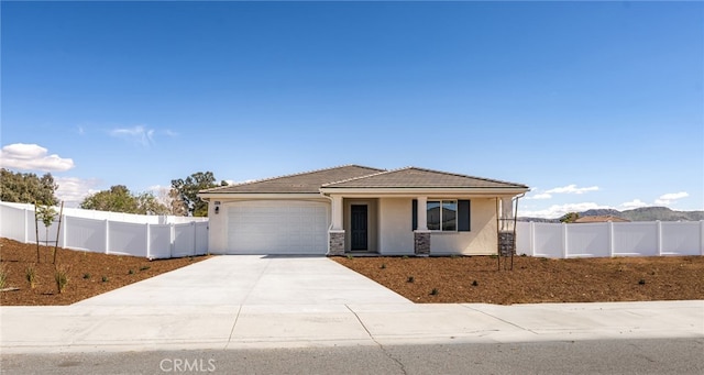 view of front of home featuring a garage, stucco siding, driveway, and fence