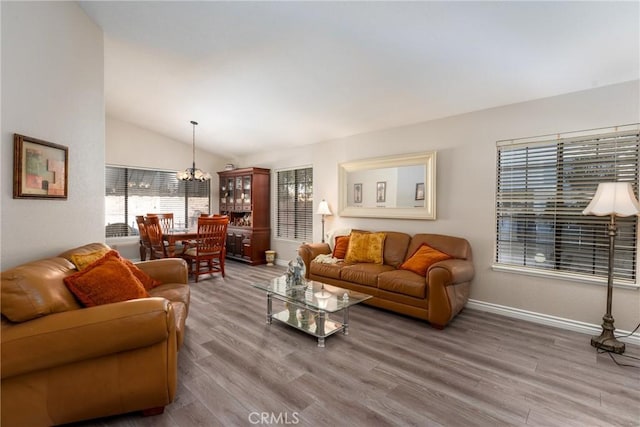 living room featuring vaulted ceiling, hardwood / wood-style floors, and a chandelier