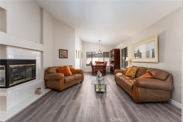 living room featuring lofted ceiling, hardwood / wood-style flooring, a fireplace, and a chandelier