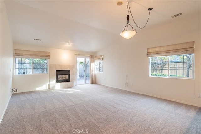 unfurnished living room featuring light carpet, a fireplace, and a healthy amount of sunlight