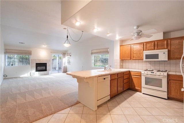 kitchen featuring sink, backsplash, tile counters, kitchen peninsula, and white appliances