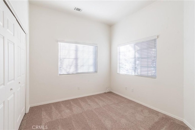 unfurnished bedroom featuring light colored carpet and a closet