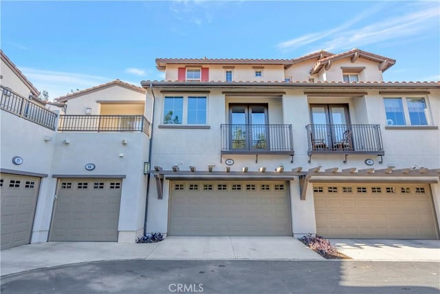 mediterranean / spanish-style home with a garage, concrete driveway, a balcony, and stucco siding