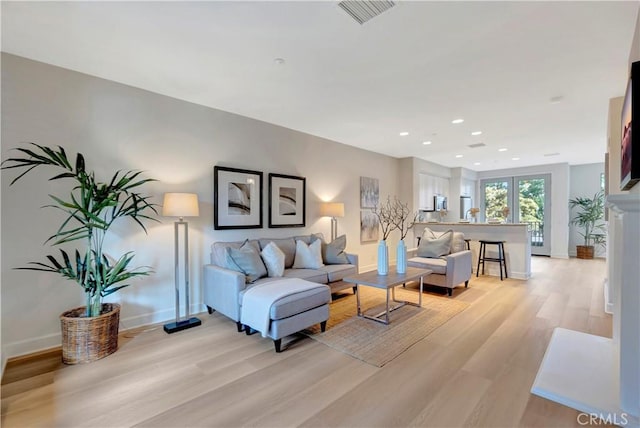 living room with recessed lighting, baseboards, visible vents, and light wood finished floors