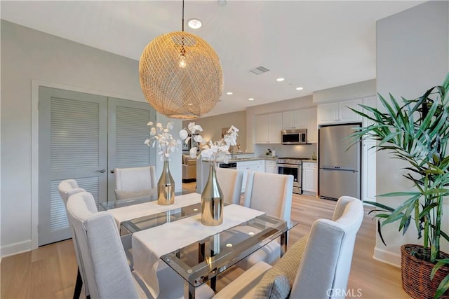 dining area with light wood-type flooring, visible vents, and recessed lighting