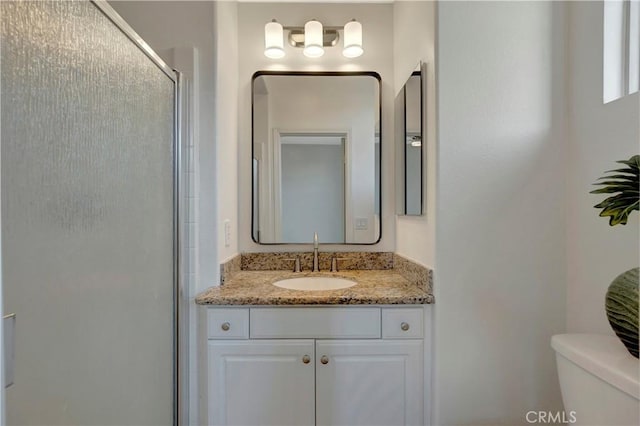 bathroom with a stall shower, vanity, and toilet