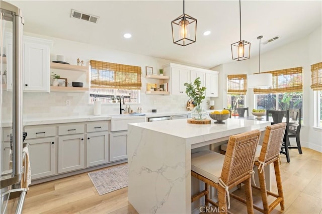 kitchen with white cabinetry, a breakfast bar area, sink, and pendant lighting