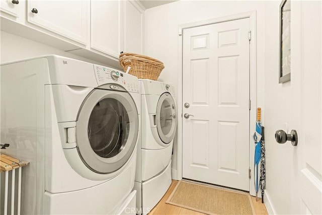 laundry area featuring cabinets, independent washer and dryer, and light hardwood / wood-style flooring