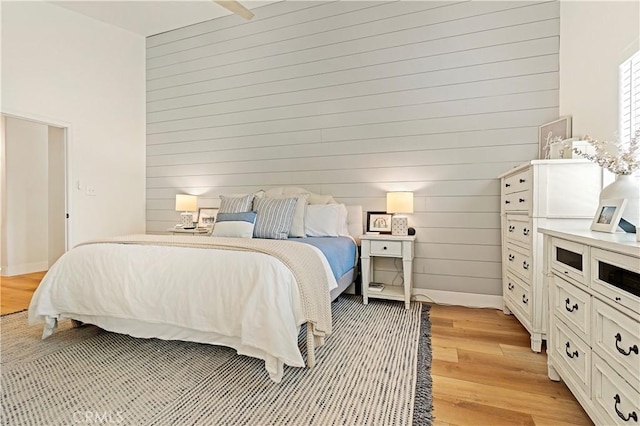 bedroom featuring wooden walls and light wood-type flooring