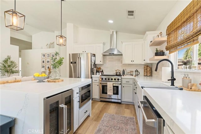 kitchen featuring pendant lighting, wall chimney range hood, white cabinetry, high end appliances, and beverage cooler