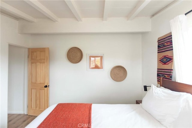 bedroom featuring light hardwood / wood-style flooring and beamed ceiling