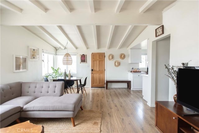 living room featuring vaulted ceiling with beams and light hardwood / wood-style flooring