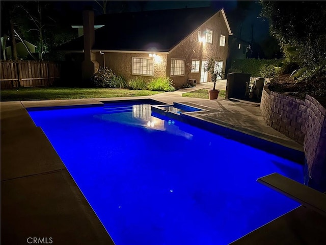 pool at night featuring a patio, fence, and a fenced in pool