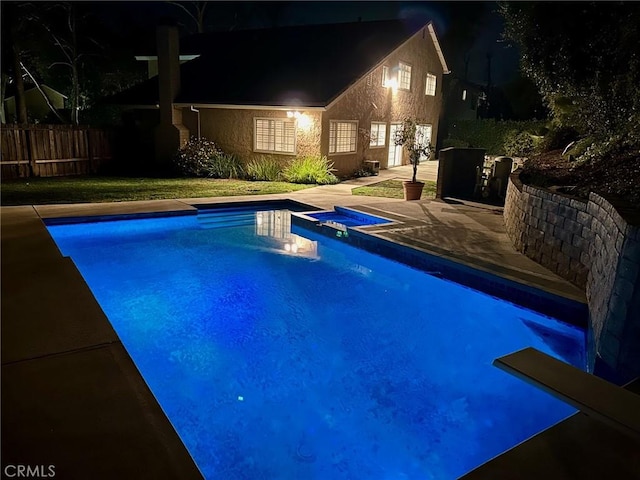 pool at twilight featuring a patio, a pool with connected hot tub, and fence