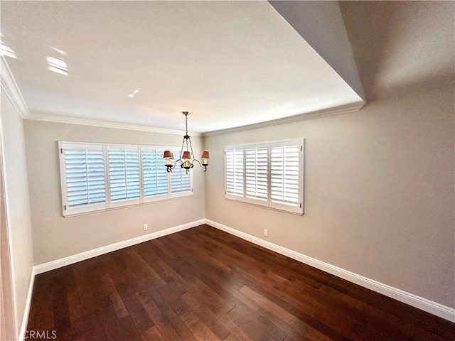 spare room with a chandelier, baseboards, dark wood-style flooring, and ornamental molding