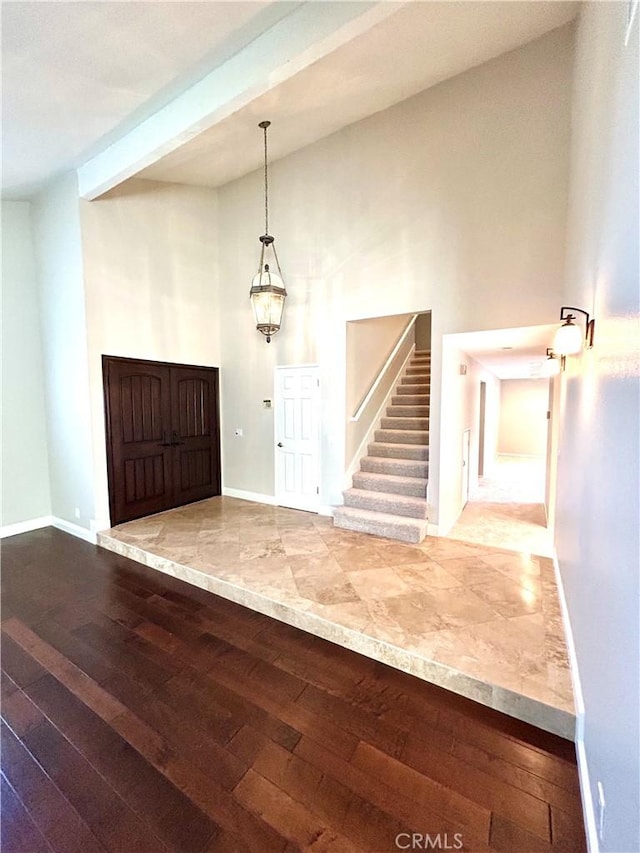 entrance foyer with hardwood / wood-style floors, stairway, baseboards, and a towering ceiling