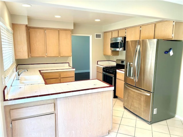 kitchen with visible vents, light brown cabinets, a sink, stainless steel appliances, and a peninsula