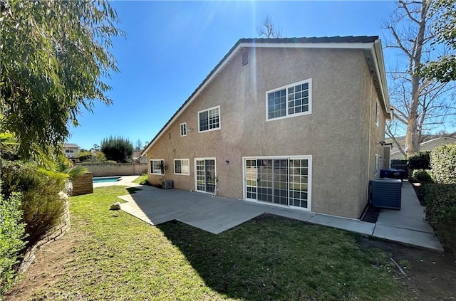 rear view of property featuring stucco siding, fence, a yard, central AC unit, and a patio area