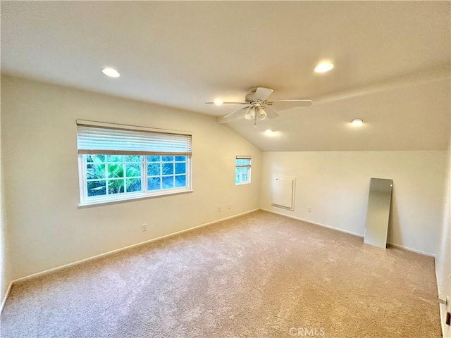 bonus room featuring lofted ceiling, plenty of natural light, a ceiling fan, and light colored carpet