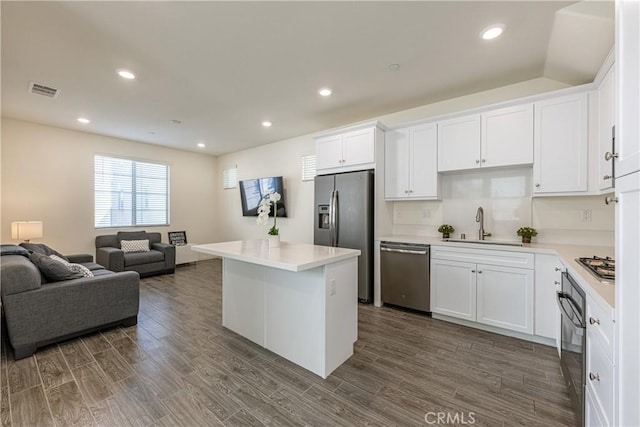 kitchen featuring sink, appliances with stainless steel finishes, dark hardwood / wood-style floors, a kitchen island, and white cabinets