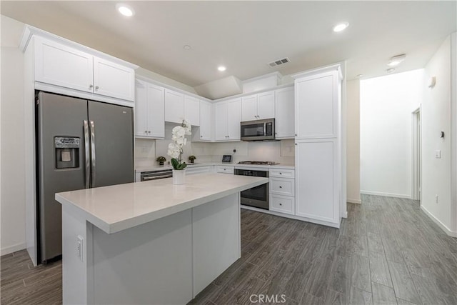 kitchen featuring appliances with stainless steel finishes, dark hardwood / wood-style flooring, a center island, and white cabinets