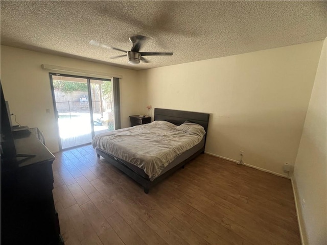 bedroom featuring dark wood-type flooring, ceiling fan, access to exterior, and a textured ceiling