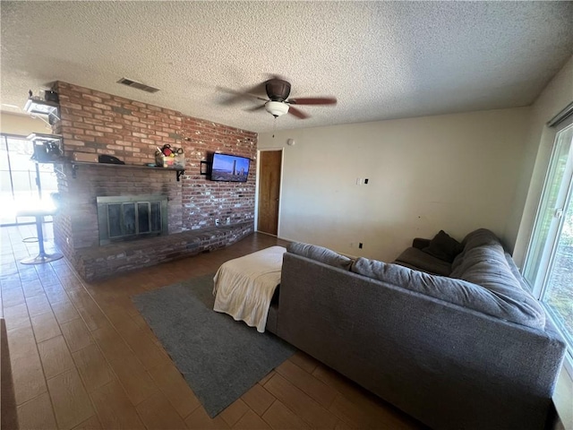 living room with plenty of natural light, dark wood-type flooring, a textured ceiling, and a fireplace