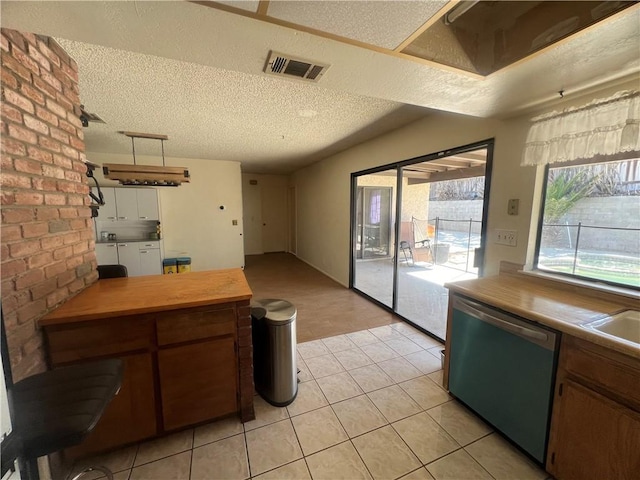 kitchen featuring dishwasher, light tile patterned flooring, a textured ceiling, and wood counters