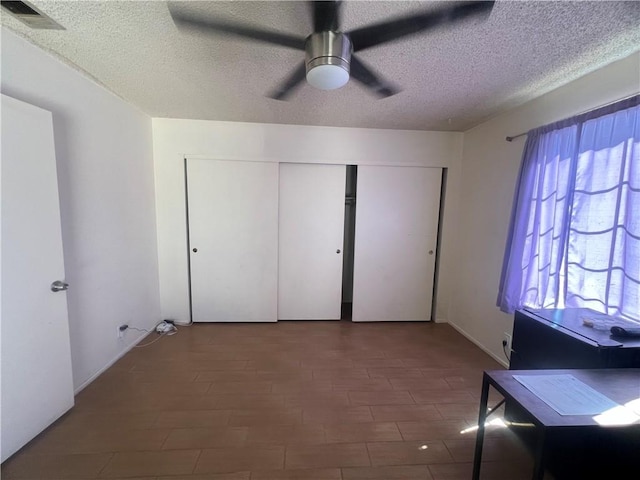 unfurnished bedroom with dark hardwood / wood-style flooring, ceiling fan, a closet, and a textured ceiling