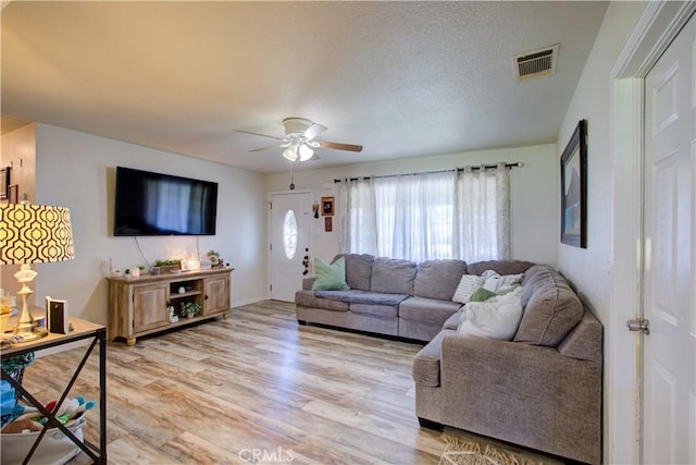 living room featuring a textured ceiling, ceiling fan, and light wood-type flooring