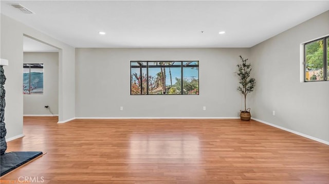 empty room with light wood-type flooring, baseboards, and recessed lighting