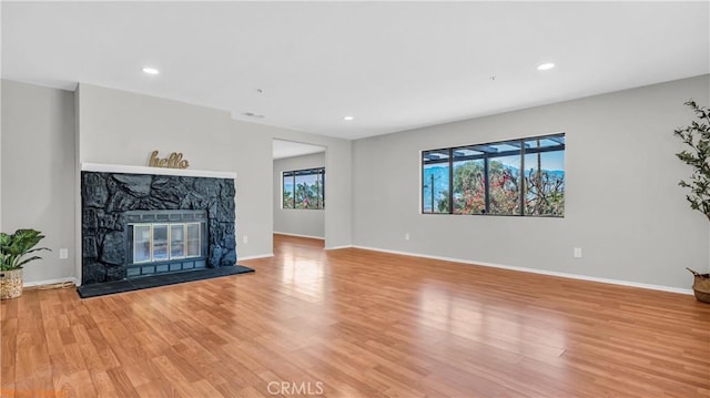 unfurnished living room featuring light wood-type flooring, a fireplace, baseboards, and recessed lighting