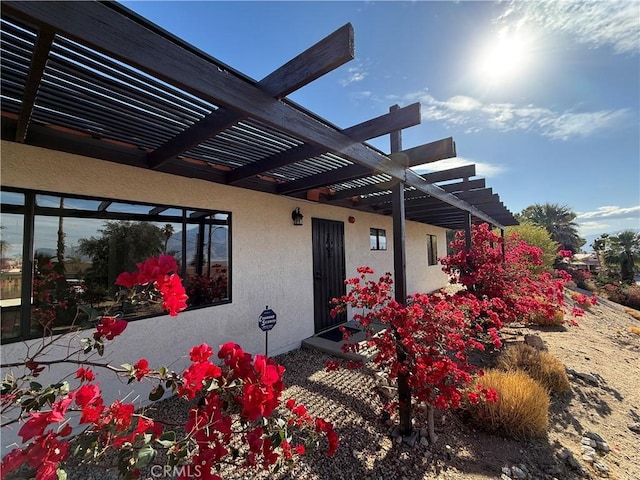 property entrance featuring a pergola and stucco siding