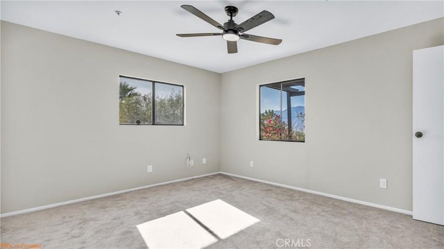 unfurnished room with baseboards, a ceiling fan, and light colored carpet