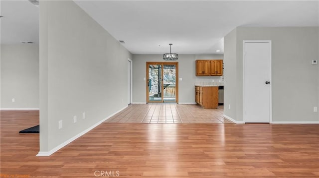 unfurnished living room with light wood-style floors, baseboards, and a notable chandelier