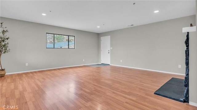 unfurnished room with light wood-type flooring and baseboards