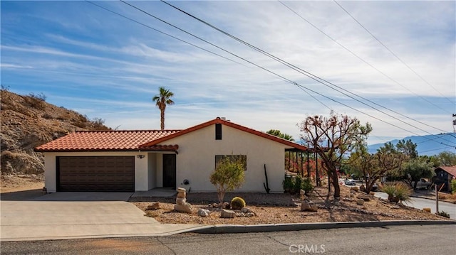 view of front of home featuring concrete driveway, a tiled roof, an attached garage, and stucco siding