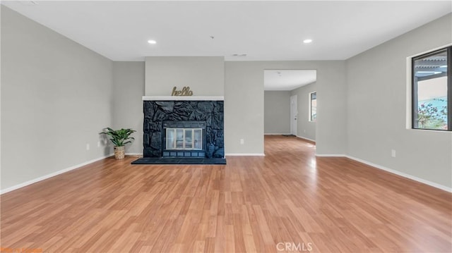 unfurnished living room with light wood finished floors, a fireplace, recessed lighting, and baseboards