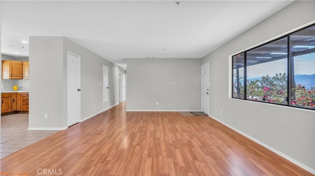 spare room featuring light wood-style floors and baseboards