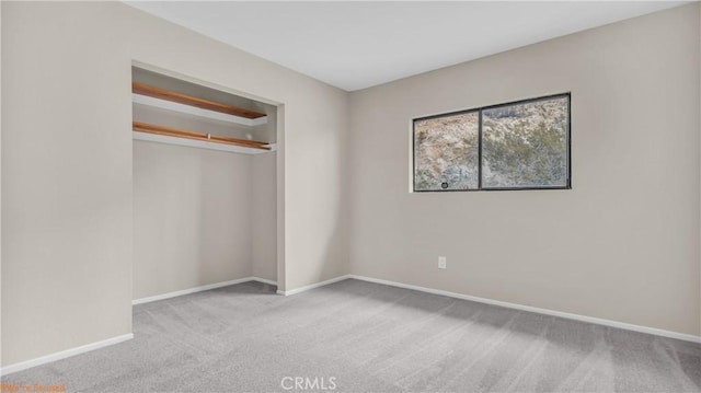 unfurnished bedroom featuring light carpet, baseboards, and a closet